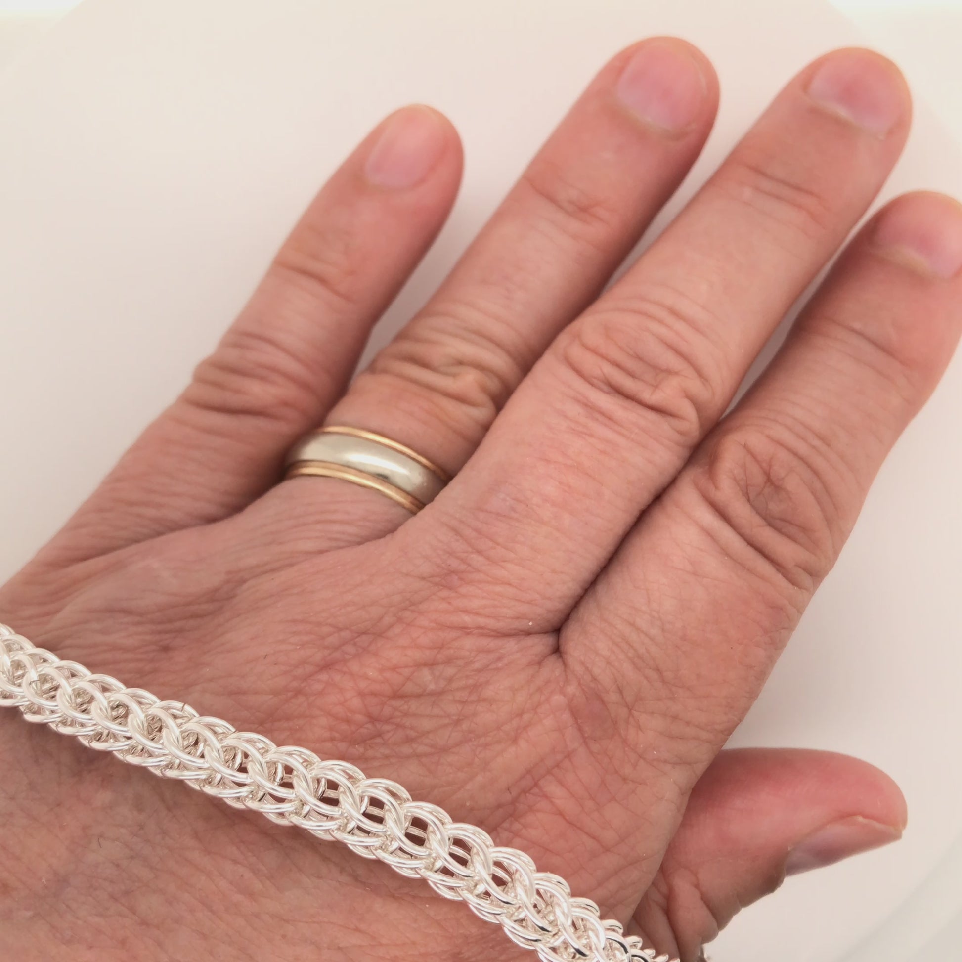 Movie, Argentium silver full Persian chain maille bracelet, rolling along hand and onto white surface.