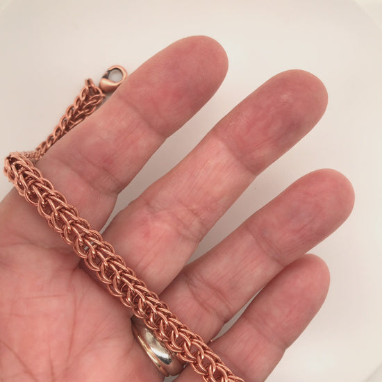 Movie of copper full Persian chain maille bracelet rolling along hand and being manipulated.